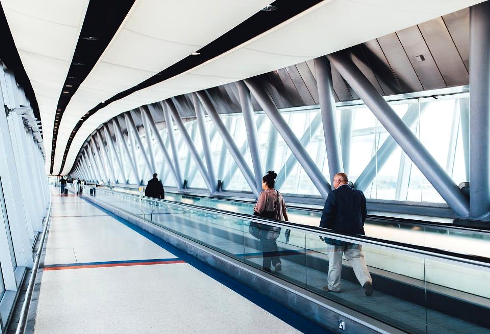 Viajantes caminhando por uma passarela envidraçada de aeroporto